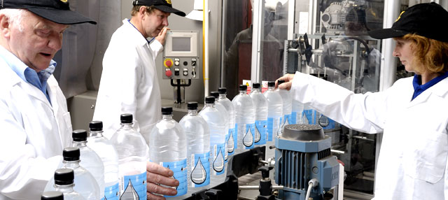 People in clean white coats working on bottling water
