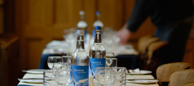 Glass bottles on a table with glasses and other table wear